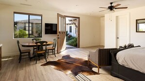 Une chambre à coucher avec un lit, un ventilateur de plafond, une fenêtre et une porte donnant sur l’extérieur.