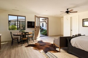 A bedroom with a bed, a ceiling fan, a window, and a door leading outside.