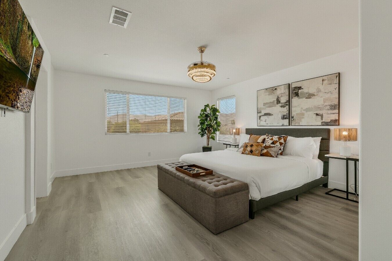 Een slaapkamer met een groot bed, een nachtkastje, een lamp en een raam met jaloezieën.