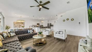 Uma sala de estar moderna com sofá, poltronas, mesa de centro e ventilador de teto.