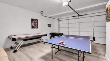 A room with a ping pong table, foosball table, and a billiards table.