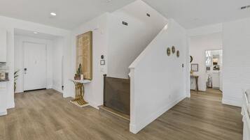 A spacious interior with a staircase leading to a loft area, a fireplace, and a kitchen visible in the background.
