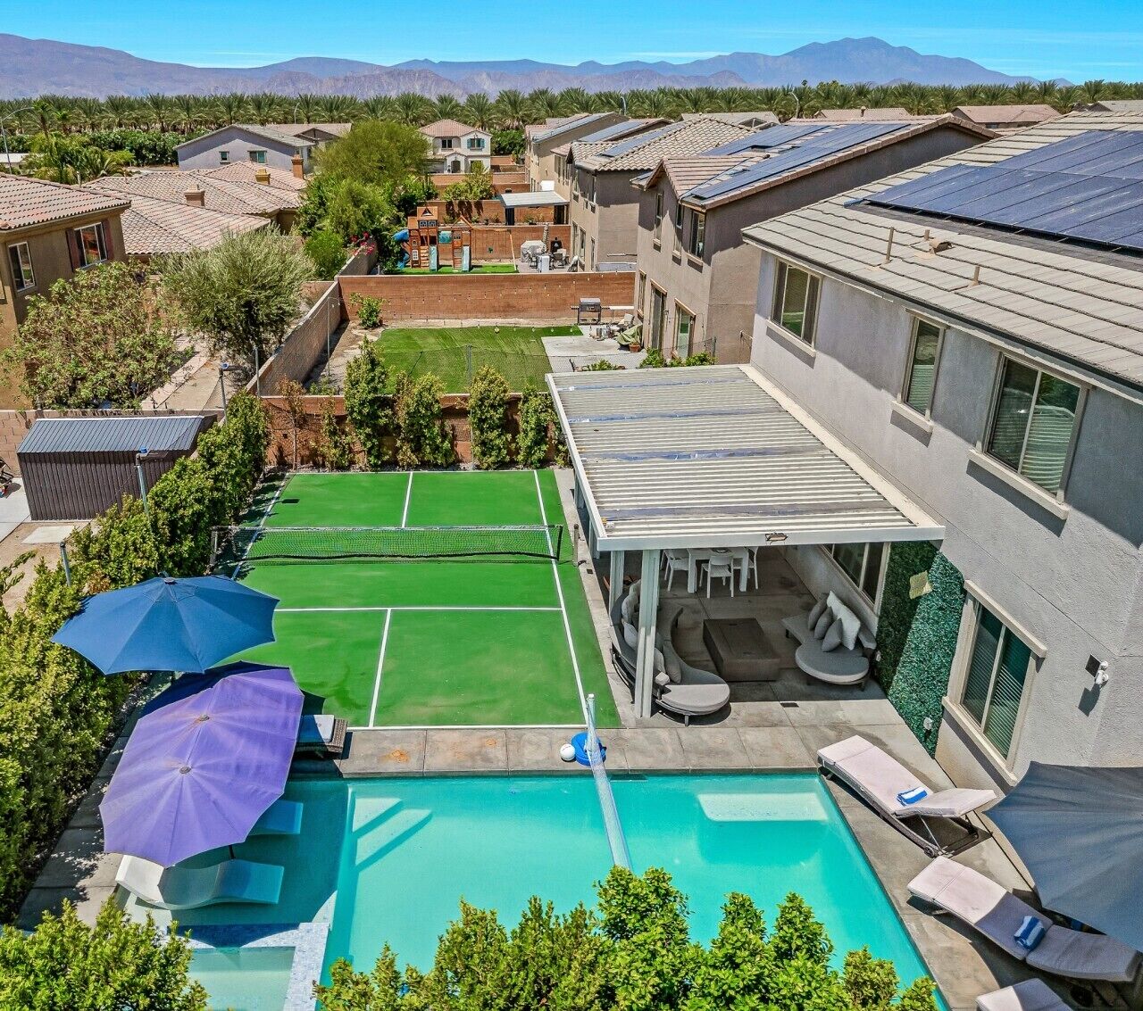 Un quartier résidentiel doté d’une piscine, de courts de tennis et d’un patio couvert avec des sièges.