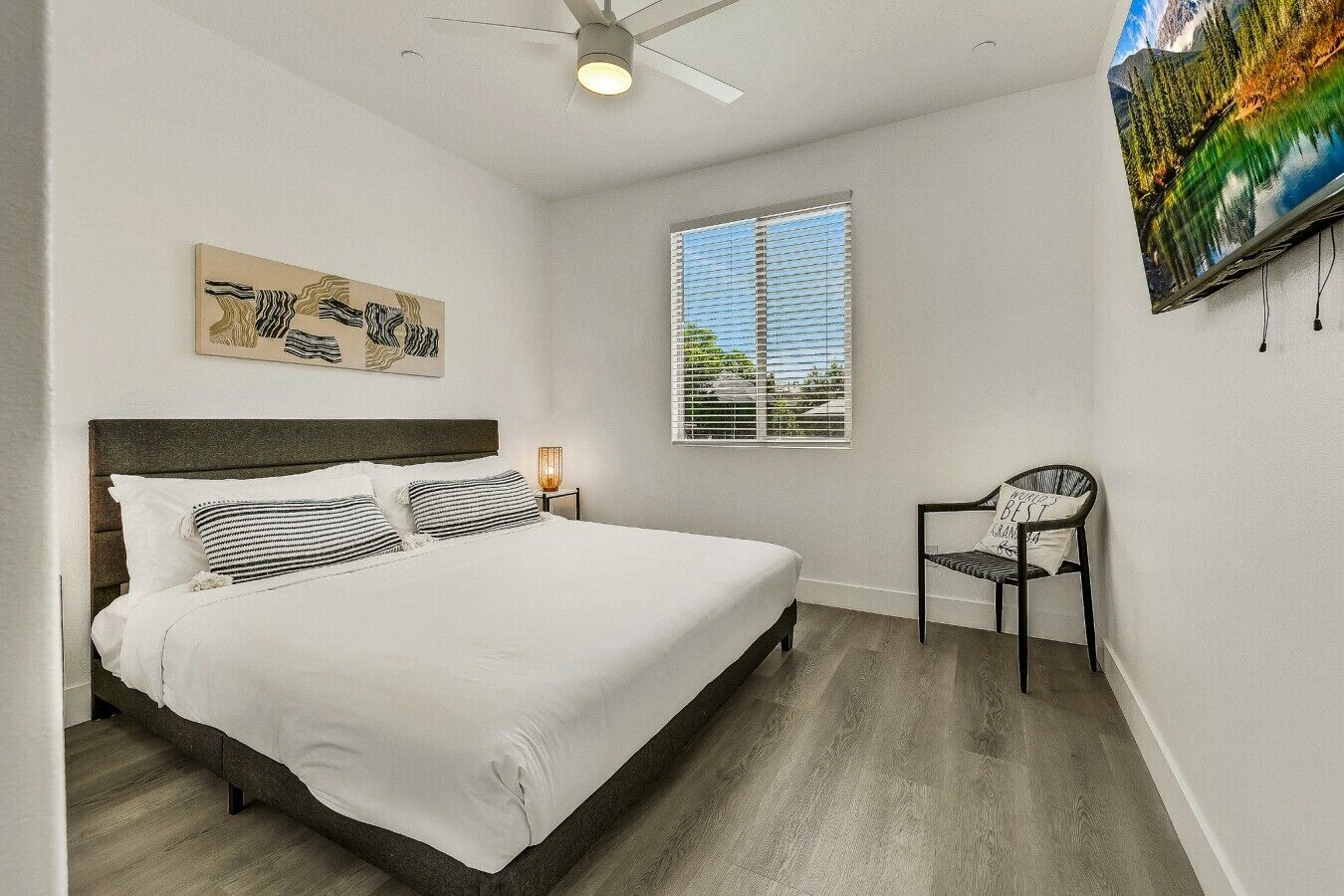 A bedroom with a bed, a chair, a window, and a ceiling fan.