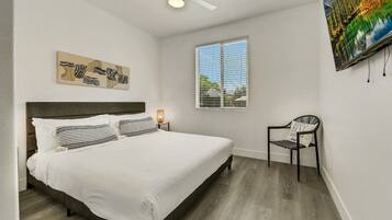 A bedroom with a bed, a chair, a window, and a ceiling fan.