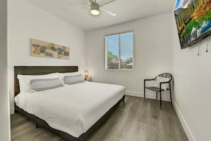 A bedroom with a bed, a chair, a window, and a ceiling fan.