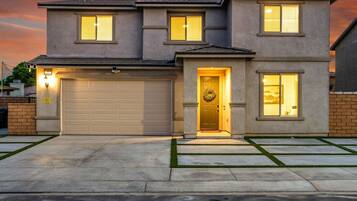A two-story residential house with a garage, a front door with a wreath, and a driveway with a lawn.