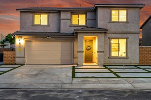 A two-story residential house with a garage, a front door with a wreath, and a driveway with a lawn.