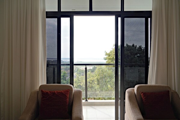A room with two armchairs facing a large window with a view of a landscape.