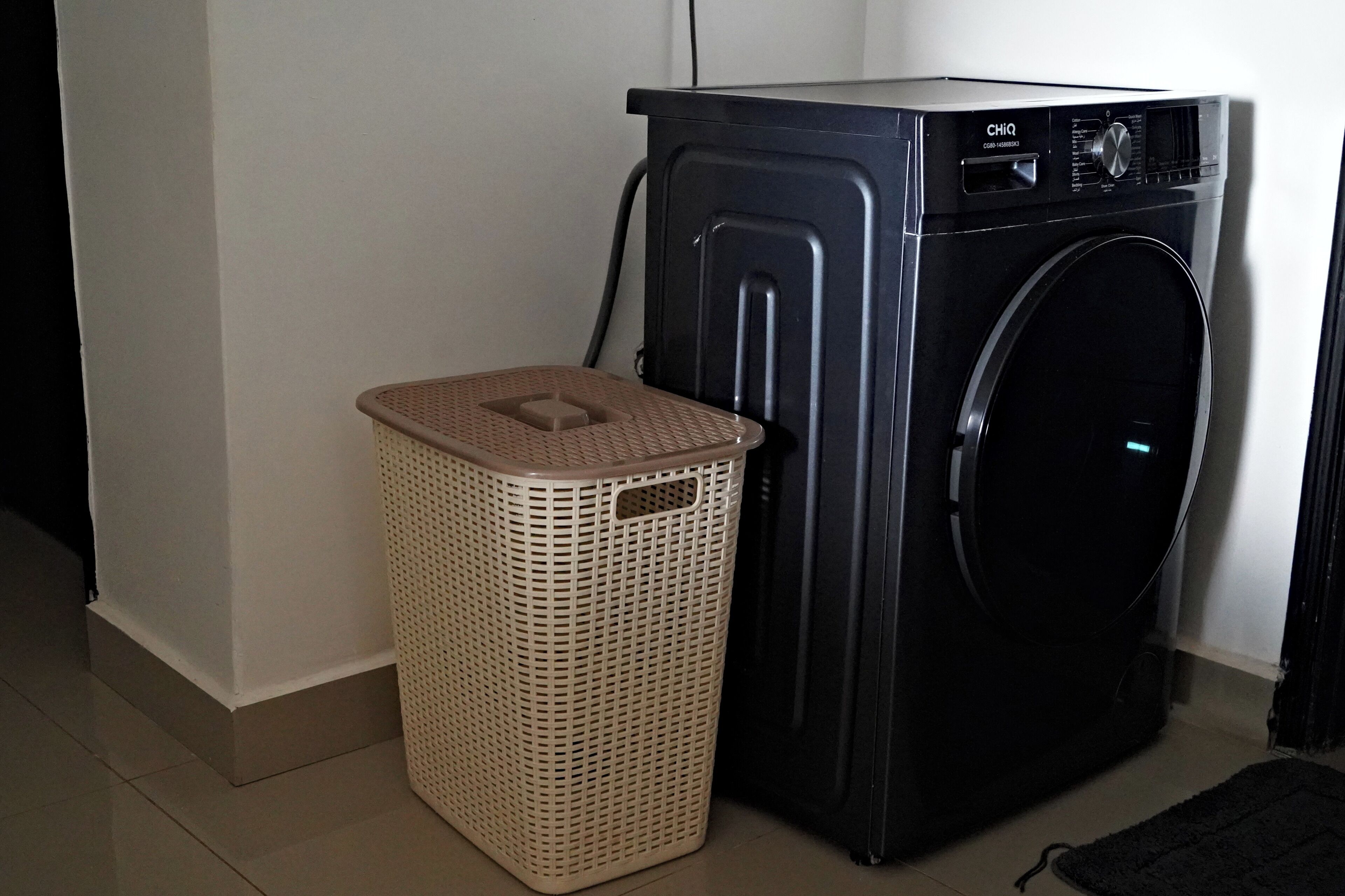 A laundry area with a washing machine and a wicker laundry basket.