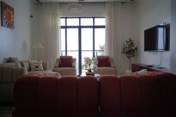 A living room with two sofas, a coffee table, a TV, and a window with curtains.