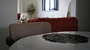 A dining table with a decorative centerpiece, a sofa, and a television mounted on the wall.