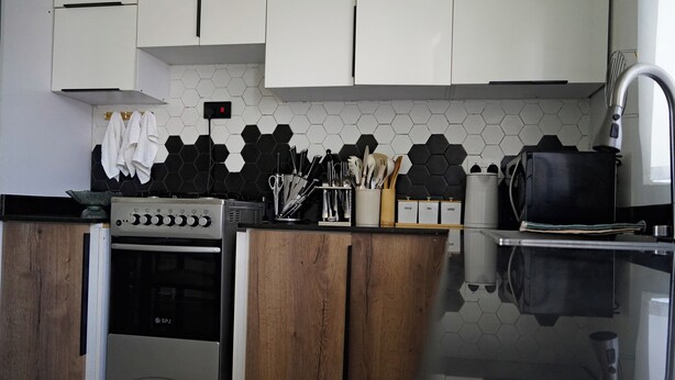 A kitchen with a stove, oven, and a variety of utensils and appliances.