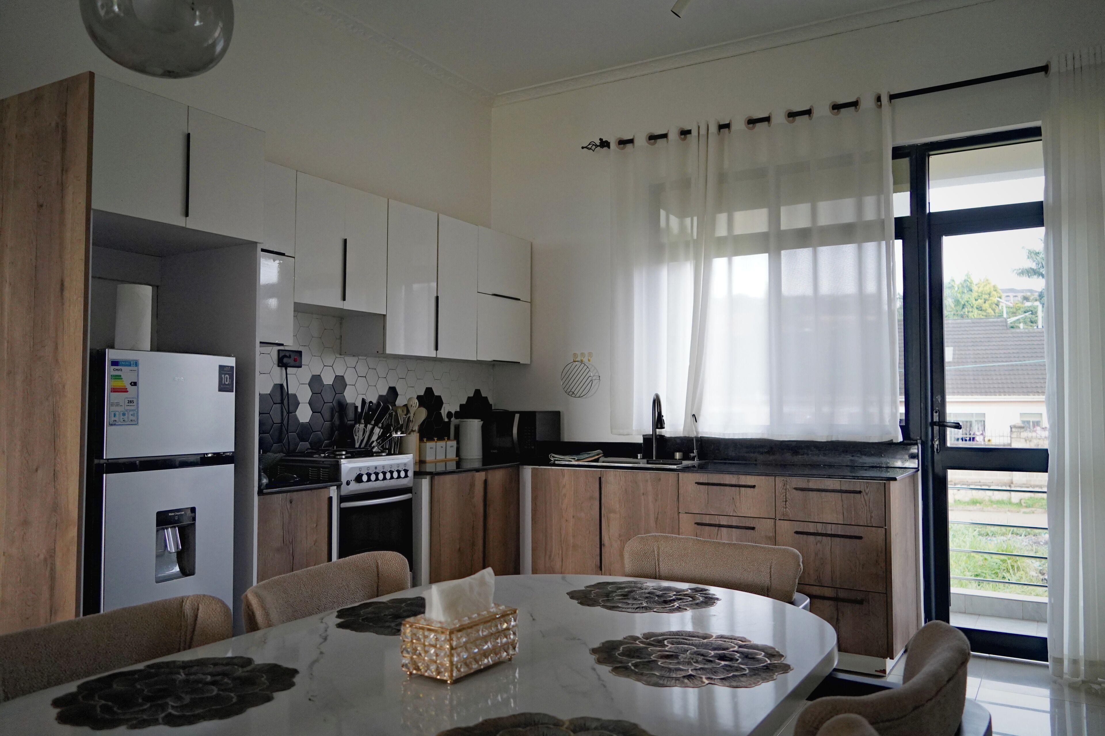 Una cuina moderna amb armaris blancs, una cuina i una zona de menjador amb taula i cadires.