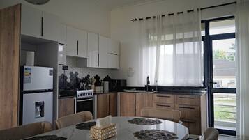 Une cuisine moderne avec des meubles blancs, une cuisinière et un coin repas comprenant une table et des chaises.