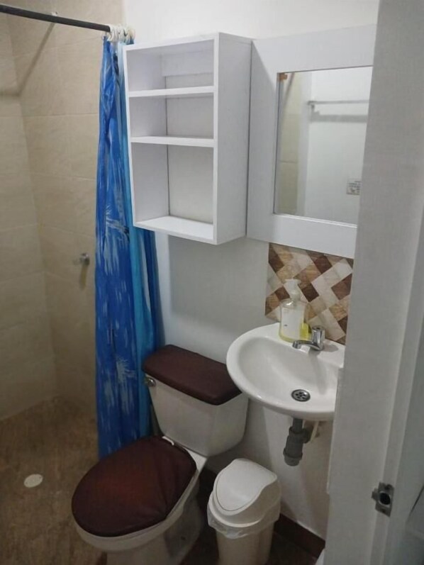 A bathroom with a toilet, sink, and a cabinet above the sink.