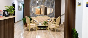 Un espace d’accueil avec un mur en marbre, un miroir, un canapé et une table basse.