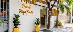 Un hostal con un letrero que dice 'Hostal Playa Bonita' y un código QR para reservar habitaciones.