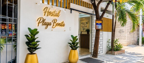 Une auberge de jeunesse avec une enseigne indiquant « Hostal Playa Bonita » et un code QR permettant de réserver une chambre.