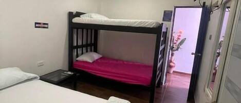 A room with a single bed, a bunk bed, a flat-screen TV, and a door leading to another room.