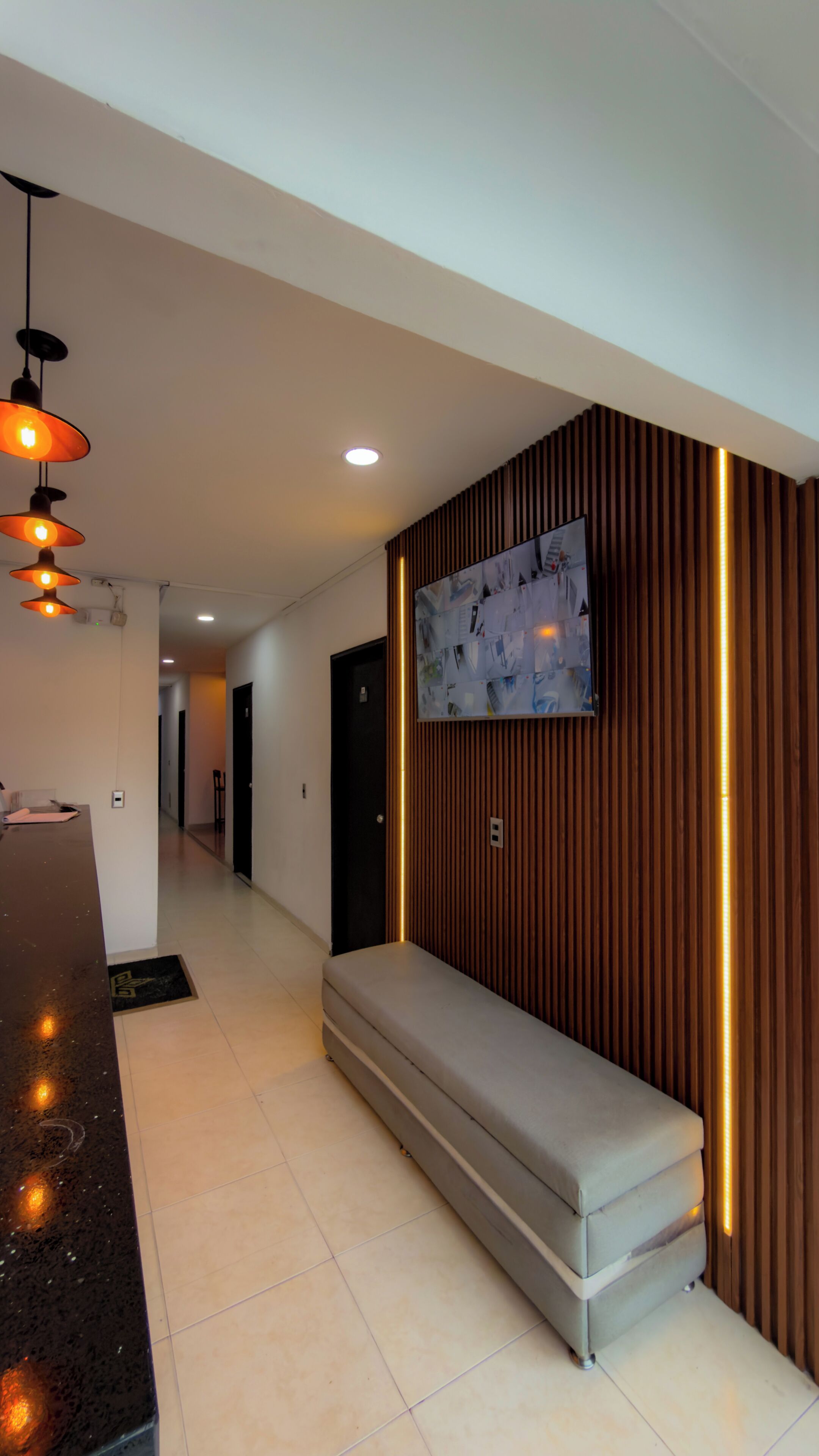 A modern interior with a bench, recessed lighting, and a wall-mounted television.