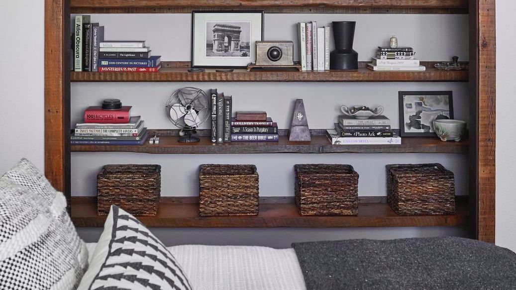 Uma estante com livros, uma câmera antiga e objetos decorativos.