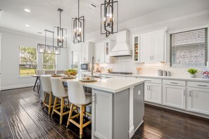 Uma cozinha moderna com ilha central, banquetas e iluminação pendente.
