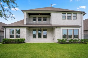 A two-story house with a balcony, large windows, and a well-maintained lawn. - Luxury League City Retreat (League City)