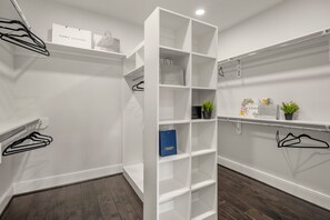 En rymlig klädkammare med vita hyllsystem, plats för att hänga kläder och en skohylla.