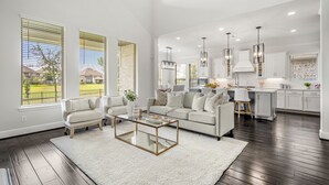 A spacious living room with a large sofa, a coffee table, and a view of the kitchen. - Luxury League City Retreat (League City)