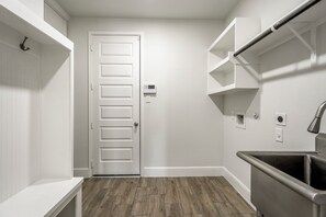 Eine saubere, moderne Küche mit Holzboden, weißen Schränken und einer Edelstahl-Spüle.