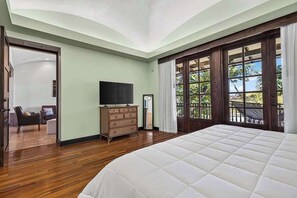 A bedroom with a large bed, a television, a dresser, and a view of the outdoors through a window. - Tropical Villa In Hacienda Pinilla (Hacienda Pinilla)