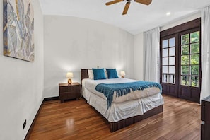 A bedroom with a bed, nightstands, a ceiling fan, and a large window with curtains. - Tropical Villa In Hacienda Pinilla (Hacienda Pinilla)
