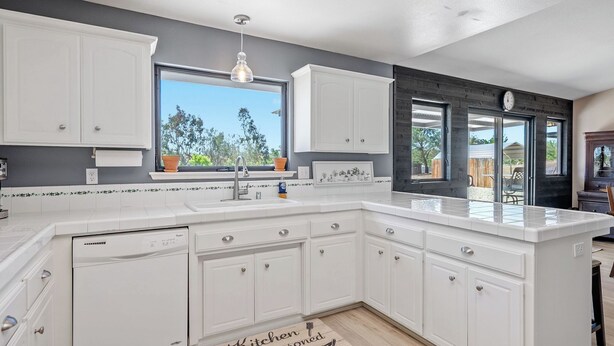 A kitchen with white cabinets, a large window, and a view of the outdoors. - Casa Merlot by Avantstay Pool Table + Firepit + BBQ Eastside Paso Wine Country (Paso Robles)
