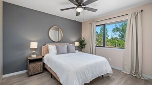 A bedroom with a bed, nightstands, a ceiling fan, a window with curtains, and a view of greenery outside. - Casa Merlot by Avantstay Pool Table + Firepit + BBQ Eastside Paso Wine Country (Paso Robles)