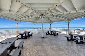 A covered outdoor seating area with picnic tables and a view of the beach. - Old Town Apartment with Parking, Walk to the Beach (Key West)