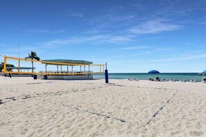 A beach volleyball court with a net, a covered seating area, and beach chairs. - Old Town Apartment with Parking, Walk to the Beach (Key West)