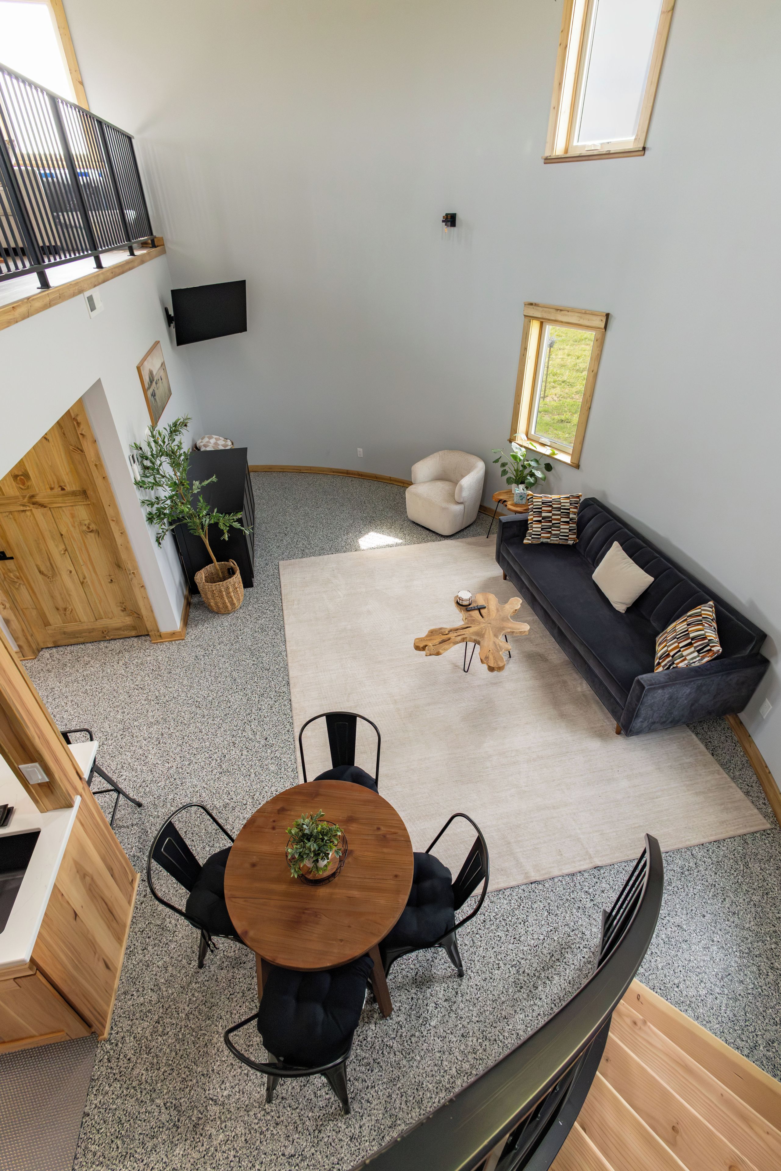 A modern interior with a dining area, a sofa set, and a staircase.