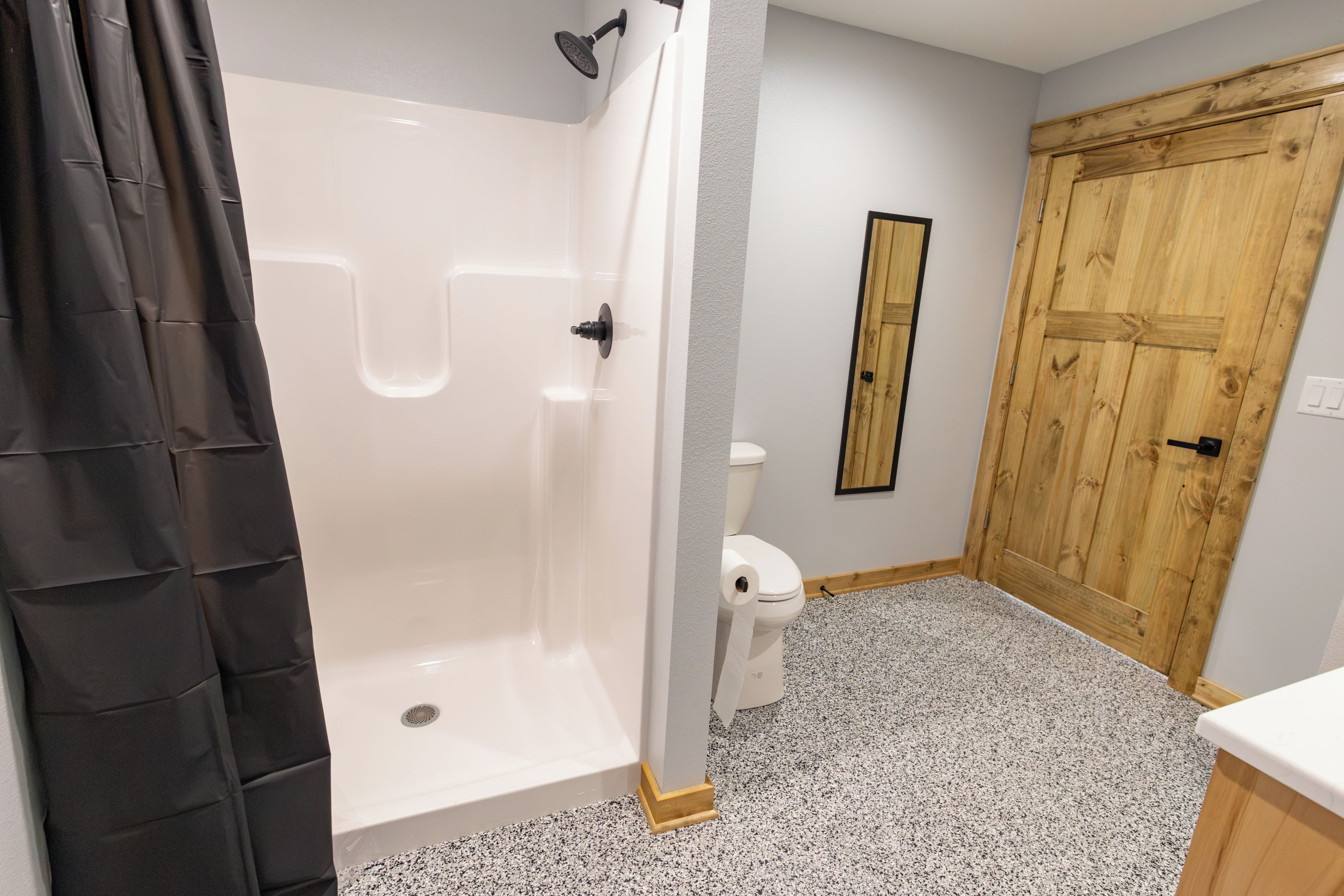 Un baño con ducha, inodoro y puerta de madera.