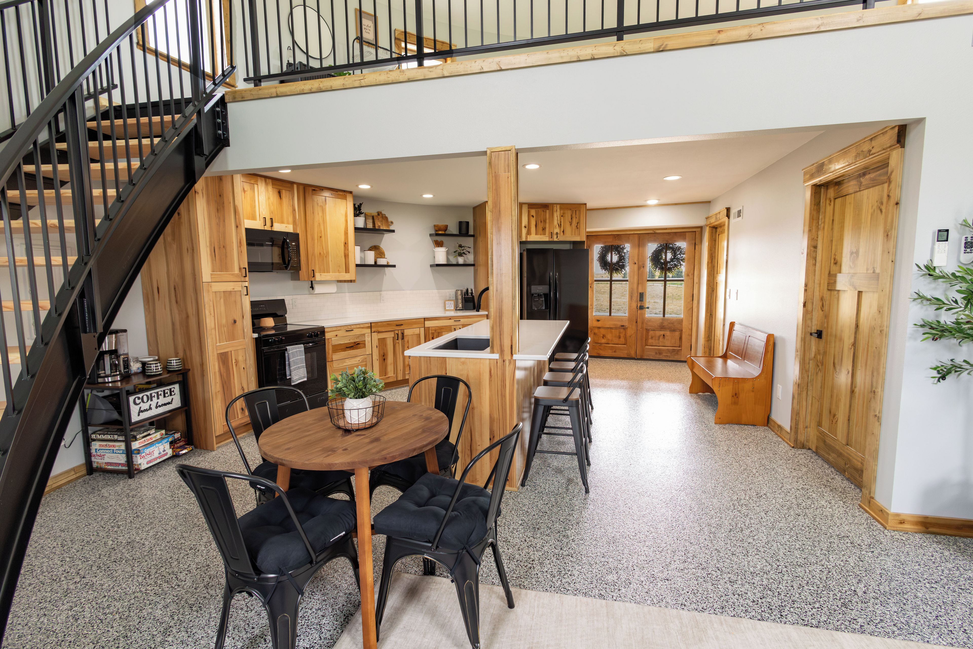 A spacious kitchen with wooden cabinets, a central island, and a dining area with chairs.