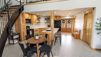 A spacious kitchen with wooden cabinets, a central island, and a dining area with chairs.