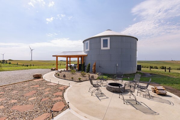 A large cylindrical building with a covered outdoor seating area and a fire pit.
