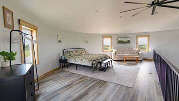 A bedroom with a bed, a bench, a sofa, and a desk with a plant.