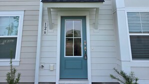A multi-story residential building with a teal front door, white window frames, and a small porch area. - Bright & Cozy 3BR Near Historic Summerville (Summerville)