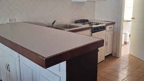 A kitchen with a large island, white cabinets, a gas stove, and a herringbone-patterned backsplash.