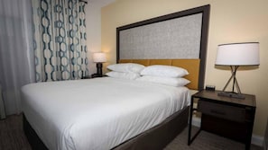 Ein Hotelzimmer mit einem großen Bett, einem Kopfteil, zwei Nachttischen mit Lampen und einem Vorhang mit geometrischem Muster.