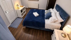 A bedroom with a bed, bedside table, lamp, and a mirror on the wall. - Mauldeth Boutique House (Manchester)