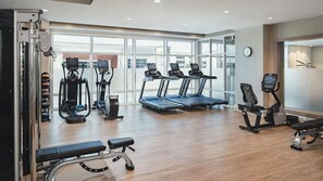 Un gimnasio con cintas de correr, elípticas y pesas libres.