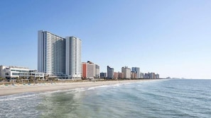 Un hotel frente a la playa con un edificio de gran altura, playa y océano.