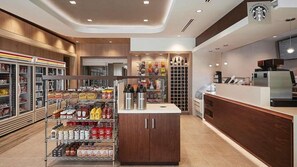 En modern kaféinredning med en bemannad dryckesstation, kylda vitrinskåp och en kaffemaskin.